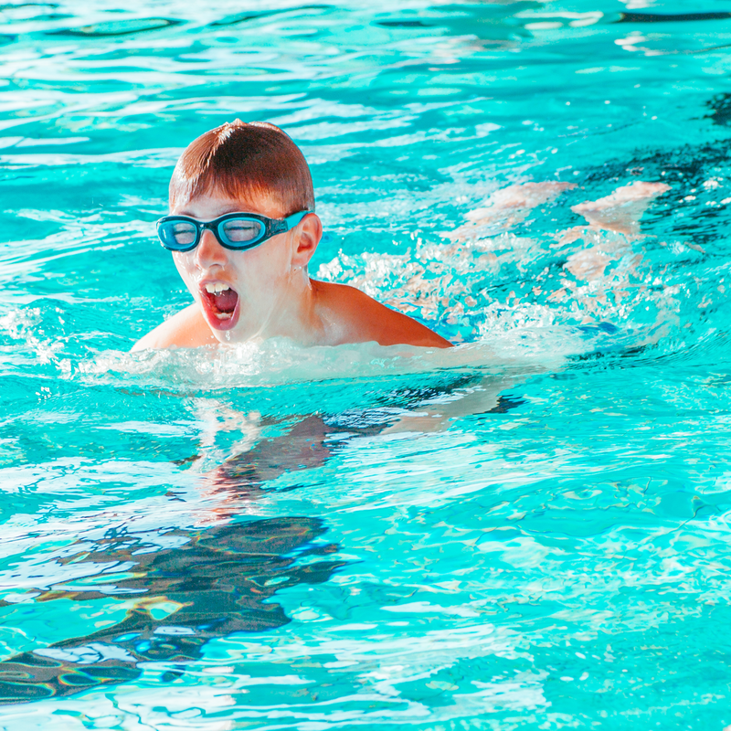 Junge schwimmt im Hallenbad